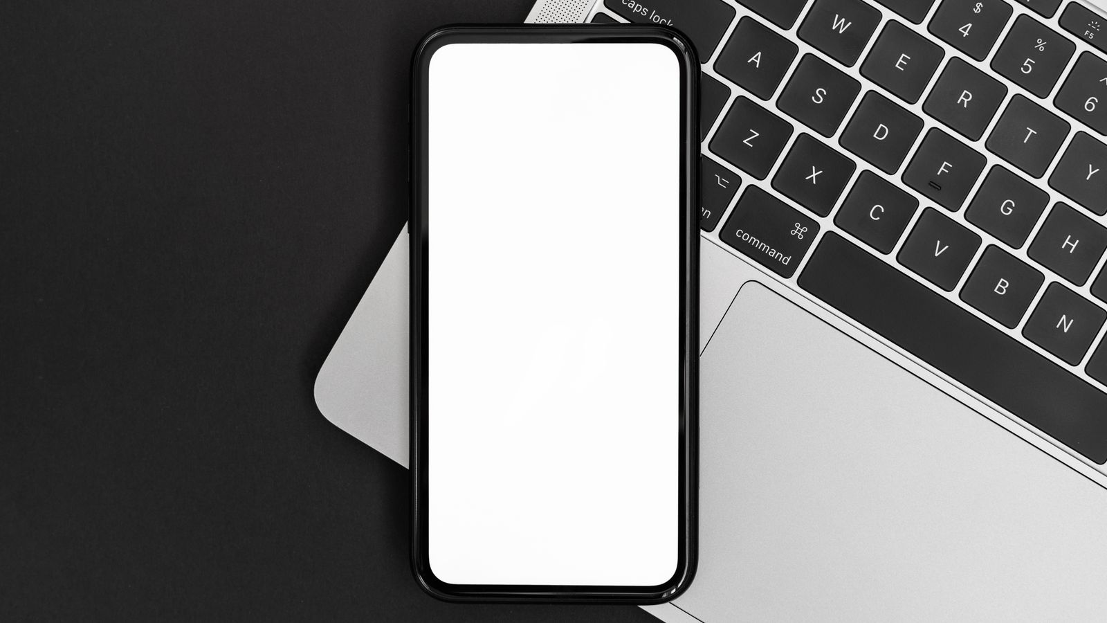 Smartphone ao lado de um notebook em uma mesa de trabalho